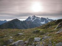 a group of hikers trekking down the trail of high alpine mountains at sunset