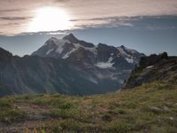 a group of hikers trekking down the trail of high alpine mountains at sunset