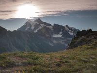 a group of hikers trekking down the trail of high alpine mountains at sunset