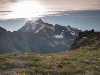 a group of hikers trekking down the trail of high alpine mountains at sunset