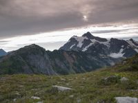 a group of hikers trekking down the trail of high alpine mountains at sunset