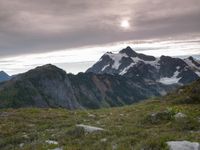 a group of hikers trekking down the trail of high alpine mountains at sunset