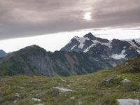 a group of hikers trekking down the trail of high alpine mountains at sunset