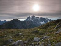 a group of hikers trekking down the trail of high alpine mountains at sunset