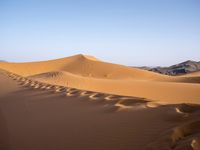 people hiking in the desert with vehicles on them with dirt terrain surrounding them and sand dunes