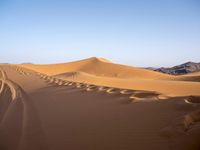 people hiking in the desert with vehicles on them with dirt terrain surrounding them and sand dunes