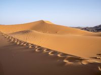 people hiking in the desert with vehicles on them with dirt terrain surrounding them and sand dunes