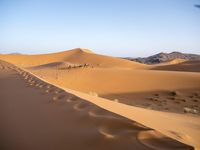 people hiking in the desert with vehicles on them with dirt terrain surrounding them and sand dunes