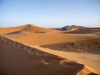 people hiking in the desert with vehicles on them with dirt terrain surrounding them and sand dunes
