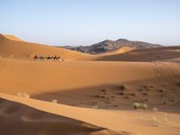 people hiking in the desert with vehicles on them with dirt terrain surrounding them and sand dunes