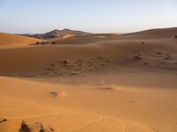 people hiking in the desert with vehicles on them with dirt terrain surrounding them and sand dunes