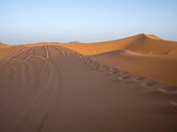 people hiking in the desert with vehicles on them with dirt terrain surrounding them and sand dunes