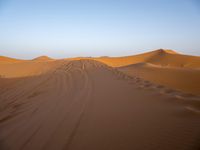 people hiking in the desert with vehicles on them with dirt terrain surrounding them and sand dunes