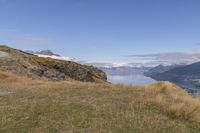 man hiking down hill beside lake and mountains in the area with mountain range and ocean