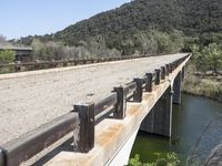 a view from a bridge overlooking trees and a mountain range of hills behind a bridge