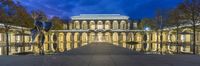 a building with glass walls and fountains in the courtyard at night lights and decorative statues