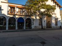 a very nice street with some trees in front of it and two large buildings with balcon