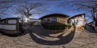 a fish eye view of a house and a small camper van by a stone sidewalk