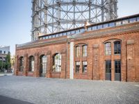 there is an old red brick building in the middle of the square with trees growing inside