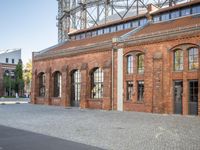 there is an old red brick building in the middle of the square with trees growing inside