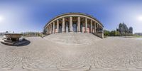 a fish eye lens looking down a stone staircase towards the domed building where people can sit