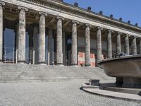 there is a large fountain next to some columns in the building on one side and another on the other