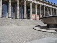 there is a large fountain next to some columns in the building on one side and another on the other