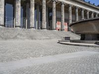 there is a large fountain next to some columns in the building on one side and another on the other