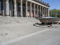 there is a large fountain next to some columns in the building on one side and another on the other