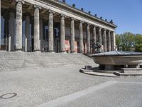 there is a large fountain next to some columns in the building on one side and another on the other