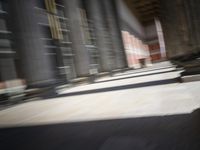 a skateboardinger moving through a tunnel between buildings in the daytime on a sunny day