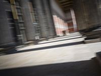 a skateboardinger moving through a tunnel between buildings in the daytime on a sunny day