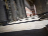 a skateboardinger moving through a tunnel between buildings in the daytime on a sunny day