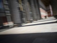 a skateboardinger moving through a tunnel between buildings in the daytime on a sunny day