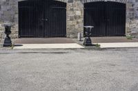 two black fire hydrant sitting in front of a stone building and on the sidewalk is a clock tower