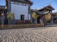 two houses and a fence on the street in town with chinese style architecture and blue sky