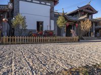 two houses and a fence on the street in town with chinese style architecture and blue sky