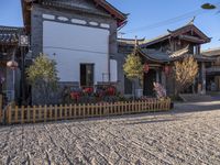 two houses and a fence on the street in town with chinese style architecture and blue sky