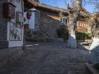 stone walkway on brick patio in old town setting with tall trees and stone buildings in background