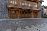 two wooden buildings sitting on the side of a street next to brick pavers and grass