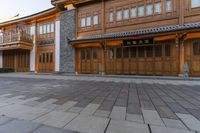 two wooden buildings sitting on the side of a street next to brick pavers and grass