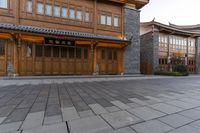 two wooden buildings sitting on the side of a street next to brick pavers and grass