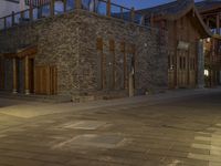 the night time view of an outdoor area with a brick building and lights glowing on