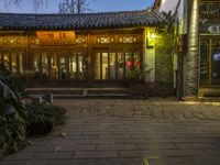 an entrance to a house on a chinese street at twilight with plants outside of the door