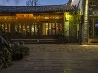 an entrance to a house on a chinese street at twilight with plants outside of the door