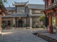 a large chinese style building with wooden doors and windows and green plants growing from brick walls and pillars