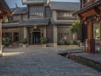 a large chinese style building with wooden doors and windows and green plants growing from brick walls and pillars