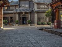 a large chinese style building with wooden doors and windows and green plants growing from brick walls and pillars