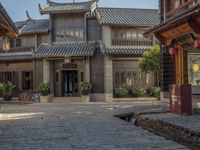 a large chinese style building with wooden doors and windows and green plants growing from brick walls and pillars