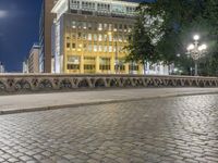 a sidewalk in front of a tall building at night with the moon lit and empty